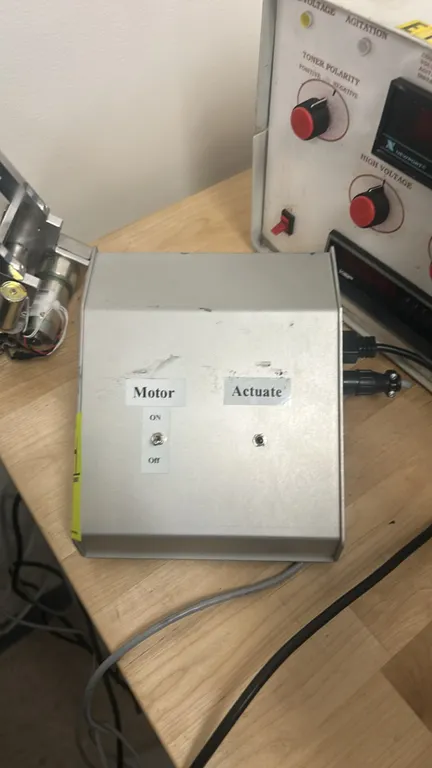 Custom control box with motorized actuator assembly. Features sloped benchtop enclosure with Motor On/Off toggle switch and Actuate switch, connected