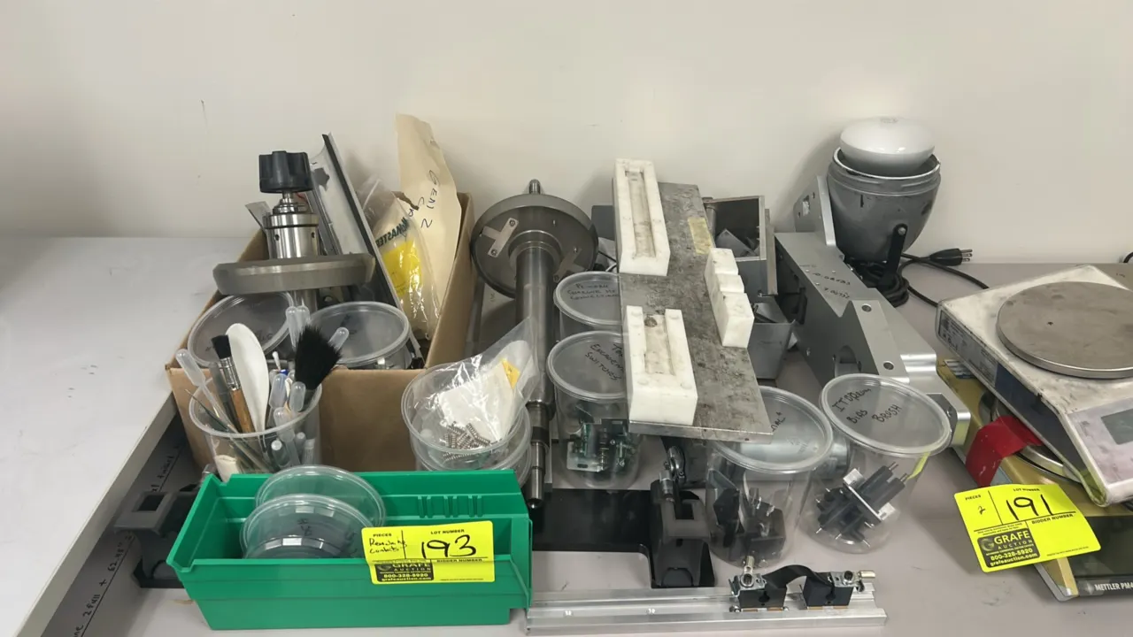 Assortment of specialized laboratory tools, components, and materials. Includes machined shafts, aluminum fixtures, mounting plates, mechanical assemb