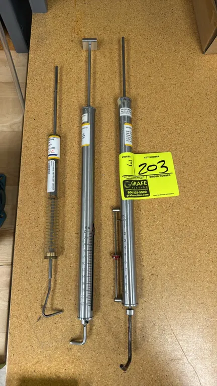Mechanical push-pull tension force gauges. Features graduated measurement scales, hooked ends, and spring-loaded plunger rods. Units include metrology