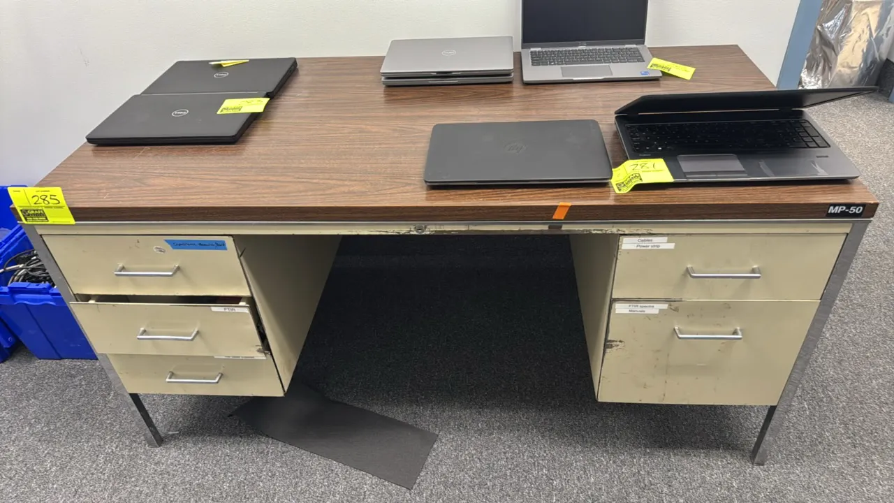 Metal double-pedestal desk. Features a woodgrain laminate top, left three-drawer pedestal, right two-drawer pedestal, and square metal legs. 60" x 30"