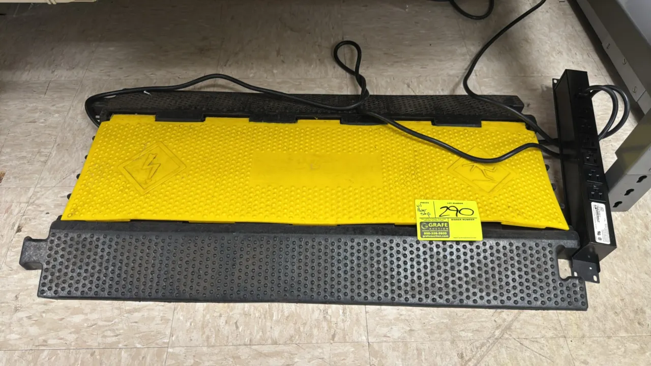 Poly cord protector with Wiremold power strip. Features a hinged yellow lid, textured ramp surface, interlocking modular tabs, and a 6-outlet metal po