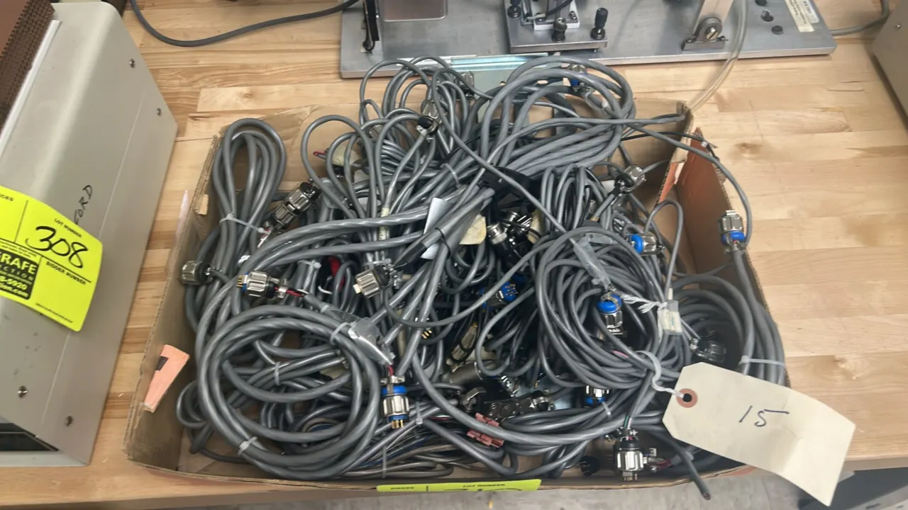Quantity of coiled gray industrial cables. Features multi-pin threaded circular connectors.
