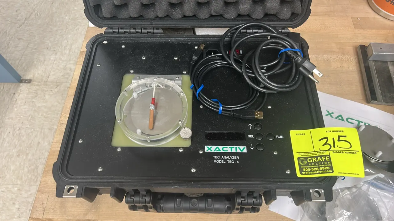 Xactiv TEC-4 tribo analyzer. Housed in a hard-shell protective transport case. Features a top sample chamber with clear cover, digital display, push-b