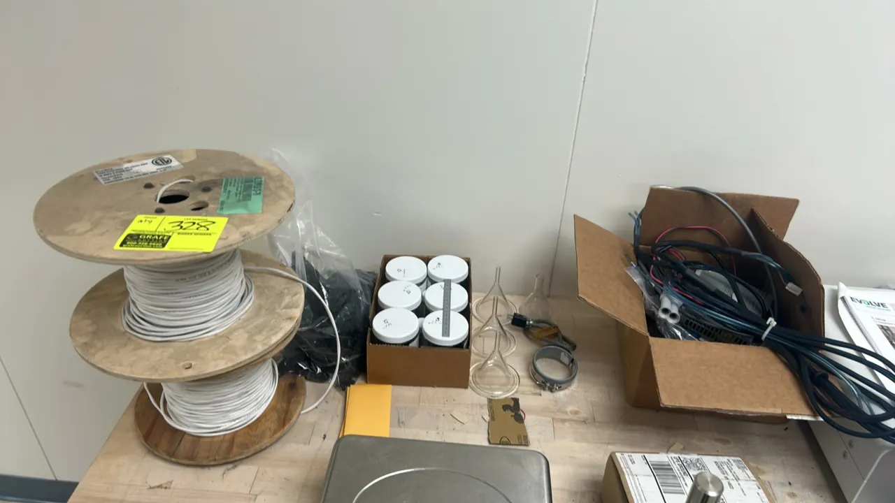 Assorted laboratory and electrical supplies lot. Includes spools of wire on wooden reels, assorted wiring harnesses and cords, short-stem glass labora