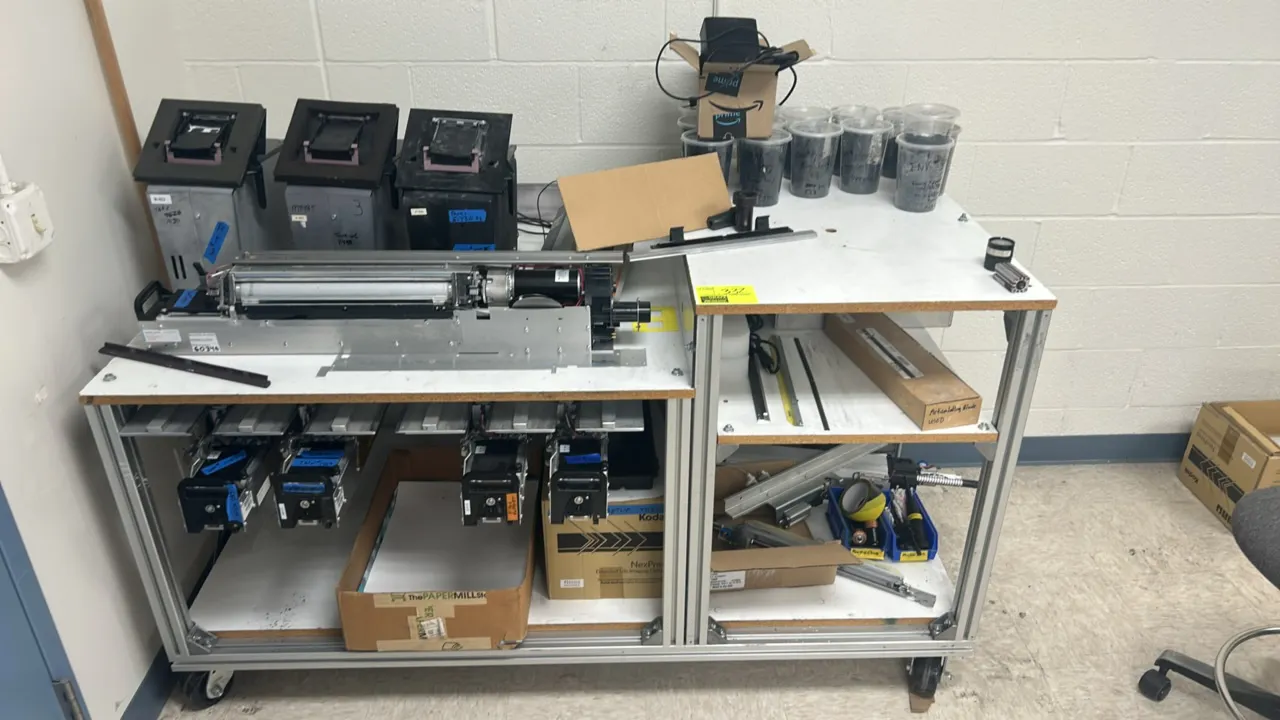 Mobile laminate cart with metal frame and Kodak NexPress 2100 digital production components. Includes NexPress extended life imaging cylinder box, dev