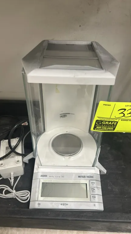 Mettler Toledo AG204 analytical balance. Features 210 g maximum capacity, 0.1 mg readability, glass draft shield enclosure, and digital display. Inclu