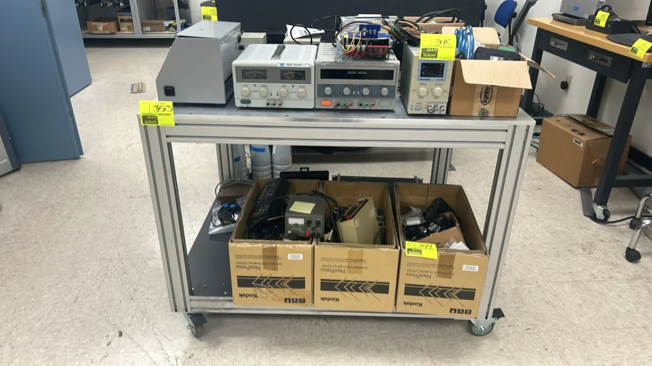 Metal 2-tier utility cart. Features aluminum extrusion frame, solid metal top, and lower shelf. 4' x 3'. Mounted on swivel casters. Contents not inclu
