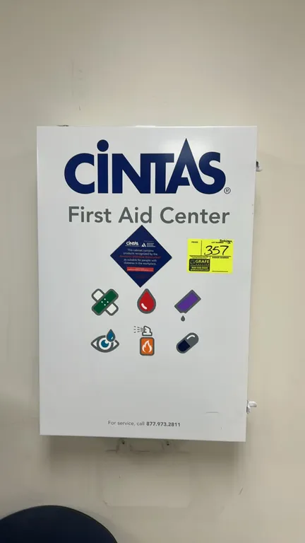 Cintas commercial First Aid Center cabinet. Features white metal construction, five interior shelves, and inner door organizer pockets with assorted f