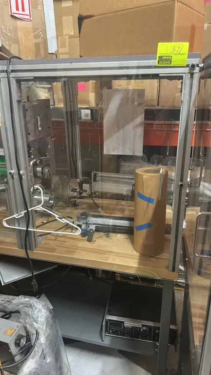 Custom industrial machinery workstation. Features an aluminum extrusion safety enclosure with clear acrylic panels, butcher block workbench top, inter