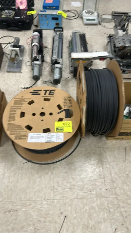 TE Connectivity Raychem spool of heat-shrink tubing. Features black heat-shrinkable polymeric tubing wound on a cardboard reel. Background items not i