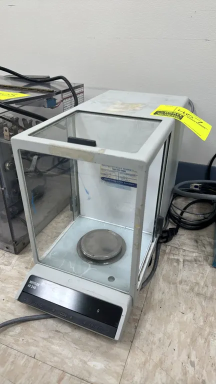 Mettler AE 240 electronic analytical lab balance. Features integrated glass draft shield with sliding access doors, round stainless steel weighing pan