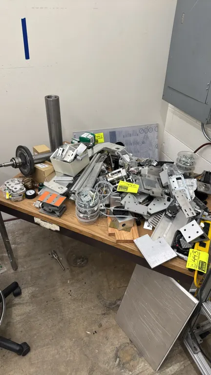Package lot of table contents including various aluminum, stainless steel, and metal components. Features machined brackets, mounting plates, extruded