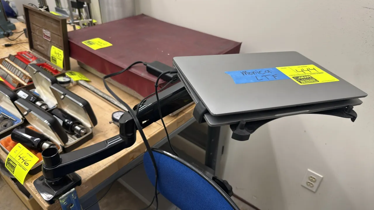 Dell 14" laptop. Features an Intel Core i7 processor, integrated webcam, and touchpad. Includes articulating desk clamp mount arm and AC power adapter