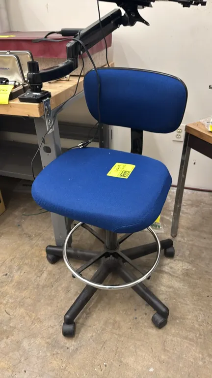 Uline upholstered laboratory drafting chair. Features blue fabric padded seat and backrest and an adjustable foot ring. Mounted on a 5-star base with