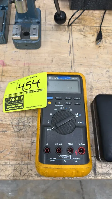 Fluke digital multimeter. Features digital LCD screen, rotary selector dial, push-button functions, and protective yellow holster with integrated tilt