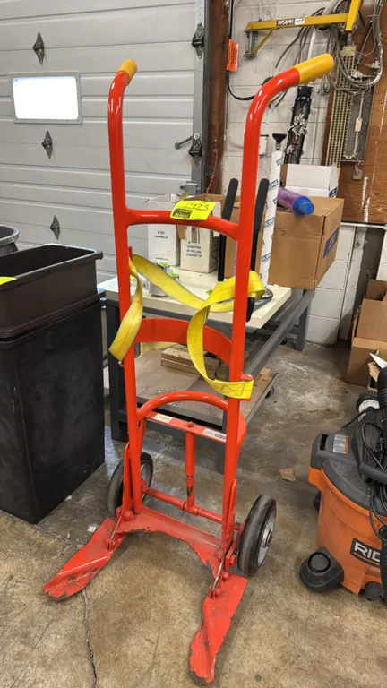 Wesco 40BT barrel dolly. Features 1,000 lb capacity, tubular steel frame, curved drum cradles, securing strap, and dual hand grips. Mounted on two sol