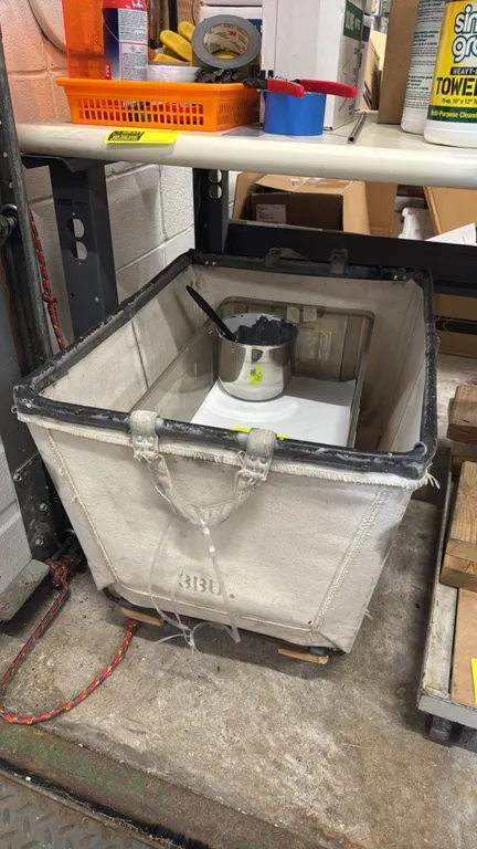 3-bushel canvas basket cart. Features canvas body with metal frame, sewn handles, and wood base with casters. Includes clear polycarbonate food pan an
