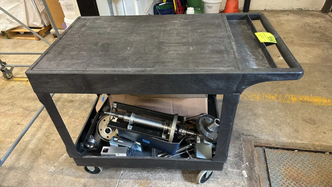 Poly 2-tier utility cart with various metal components. Features a molded handle with integrated tool tray, flat upper shelf, and lower basin shelf. I