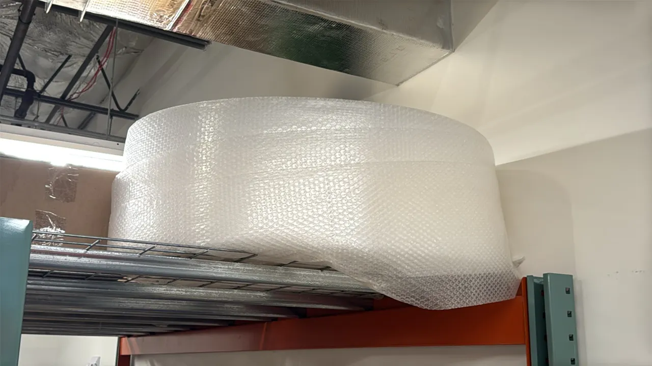 Roll of bubble wrap packaging material. Clear plastic construction with cardboard core. Pallet racking and surrounding items not included.