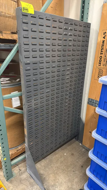 Metal louvered bin rack. Features a gray finish with louvered panels for hanging storage bins. 36"W x 67"H. Freestanding design with angled base suppo