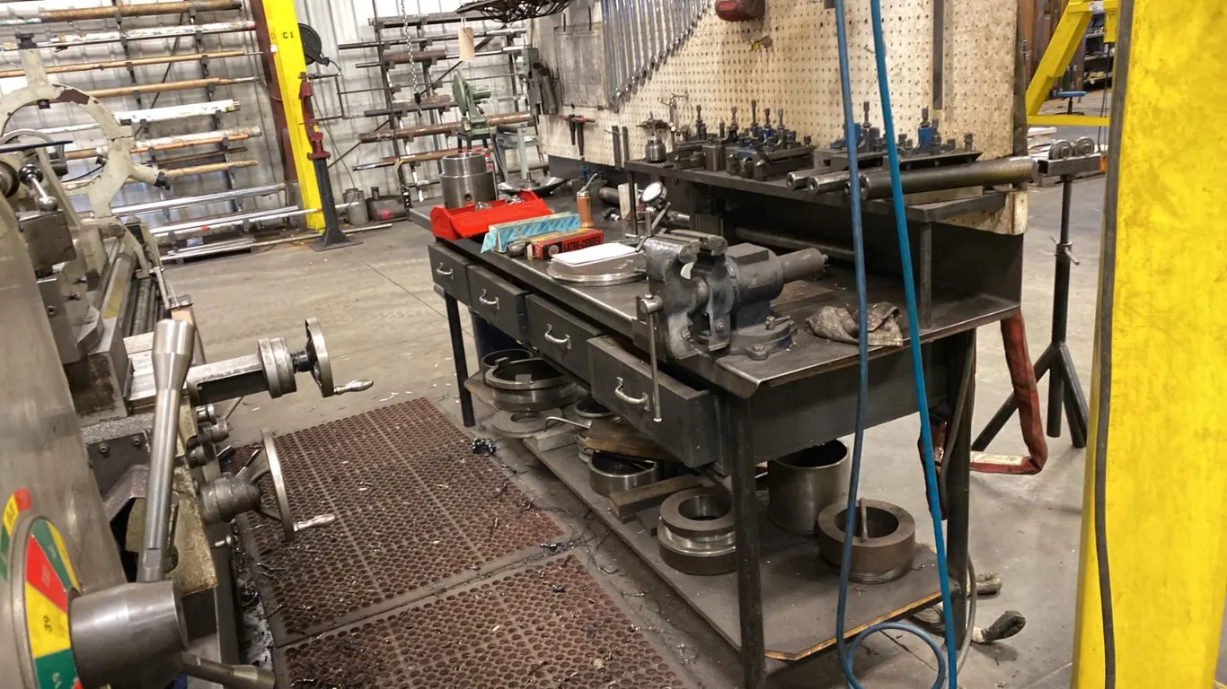 8' LONG METAL WORK BENCH WITH 5" VISE. 4' OVERHEAD LIGHT. PEG BOARD BACK