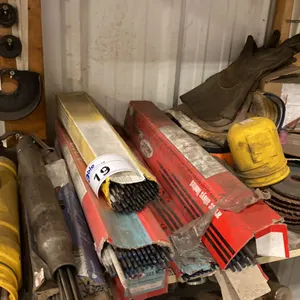 SHELF OF ASSORTED WELDING RODS AND GRINDING DISCS. WITH ROD HOLDER STAND