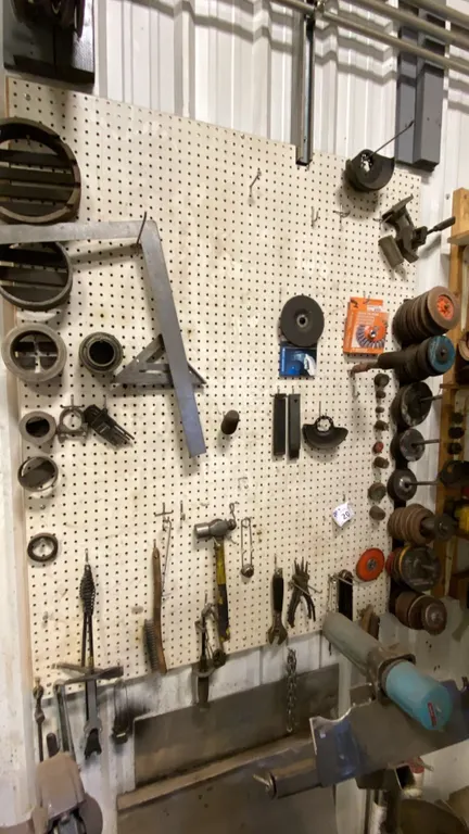 PEG BOARD WITH CONTENTS. GRINDING DISCS, SET SQUARES, HAMMERS, AS SHOWN IN PHOTO