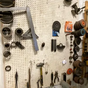 PEG BOARD WITH CONTENTS. GRINDING DISCS, SET SQUARES, HAMMERS, AS SHOWN IN PHOTO