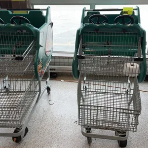 Kids grocery shopping carts. Features green molded plastic cab with dual steering wheels, seating for two, safety straps, flame decals, and upper and 