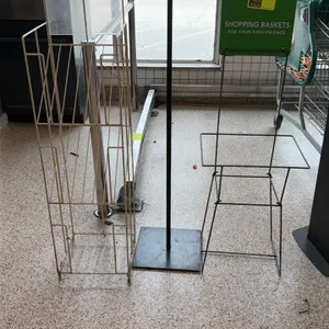 Assorted retail display racks and stands. Includes a white wire literature rack with clear header, a black metal sign stand with flat base, and a blac
