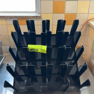 Black acrylic lid holders. Features 4-compartment slotted design with labeled size designations and tiered configuration. Designed for countertop plac