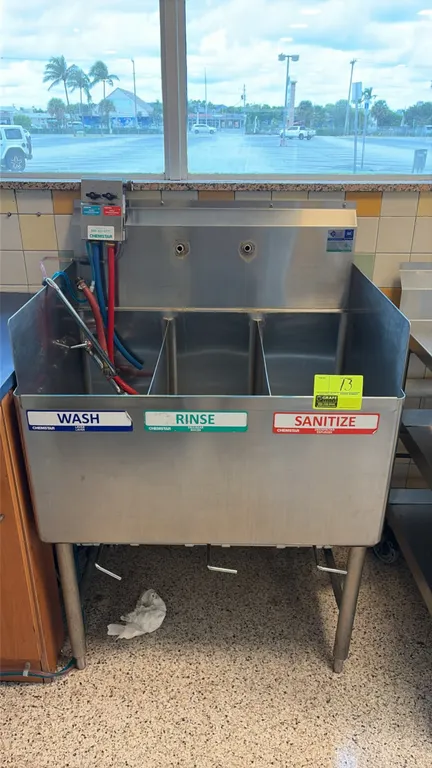 Stainless steel 3-compartment sink. Features integrated backsplash, side splashes, lever waste drain valves, and Chemstar chemical dispenser. 33 1/2"
