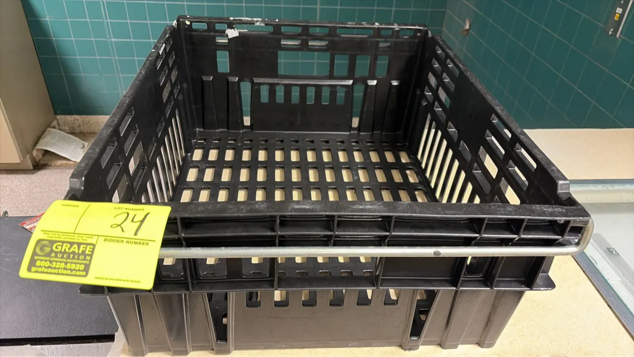 Plastic bread crate. Features molded black plastic construction, slotted sides and bottom, and a metal stacking bail bar.