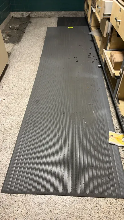 Gray rubber anti-fatigue mat runner. Features a ribbed traction surface and beveled edges. 11'L. Surrounding cabinetry and contents not included.