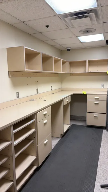 Laminate base cabinet and upper cupboard workstation. Features an L-shaped configuration with laminate countertops, backsplash, integrated drawer pede