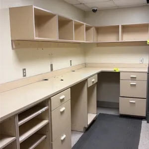 Laminate base cabinet and upper cupboard workstation. Features an L-shaped configuration with laminate countertops, backsplash, integrated drawer pede