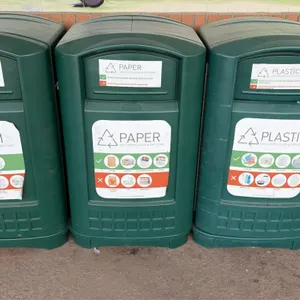 Polyethylene recycling trash cans. Features molded dark green plastic construction, front push flap waste openings, side-access service doors, and ins