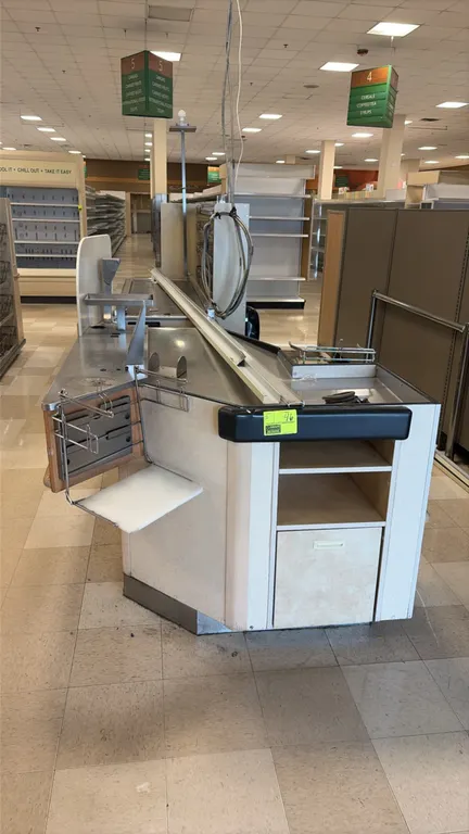 Single belt checkout lanes. Features stainless steel surfaces, conveyor belt section, bagging station with wire bag rack and folding shelf, under-coun