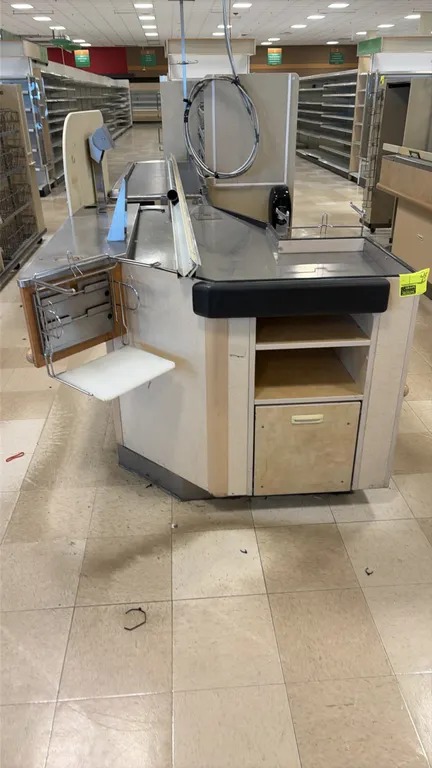 12' single belt checkout lane. Features stainless steel tops, motorized conveyor belt section, bagging platform with wire bag rack, terminal mounting