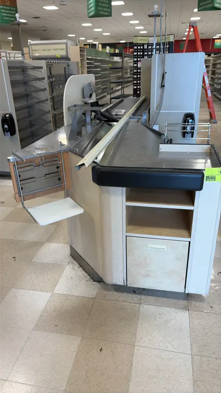 Single belt checkout lanes. Features stainless steel top surfaces, conveyor belt section, side bag rack, under-counter shelving, and lower storage com