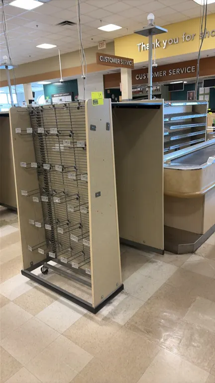 Wood laminate candy and magazine racks. Features angled wire magazine shelves, wire display baskets, endcap displays with hanging hooks, and laminate