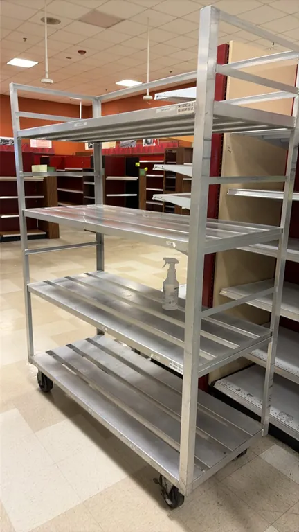 Aluminum 4-tier portable rack. Features slatted aluminum shelves. 60"L x 24"W x 78"H. Mounted on casters. Contents not included.