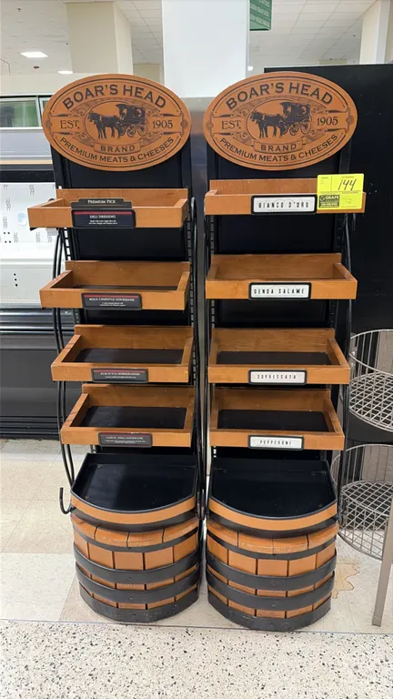 Boar's Head deli display racks. Features branded wooden oval header signs, (4) tiered wood-framed shelves with product label holders, and barrel-style