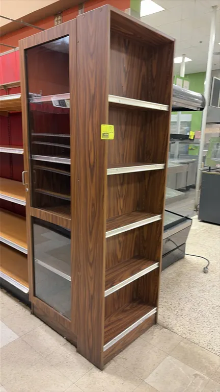 Wood laminate corner end cap display cabinet. Features woodgrain laminate finish, hinged glass display door, interior shelving, open end shelves, and