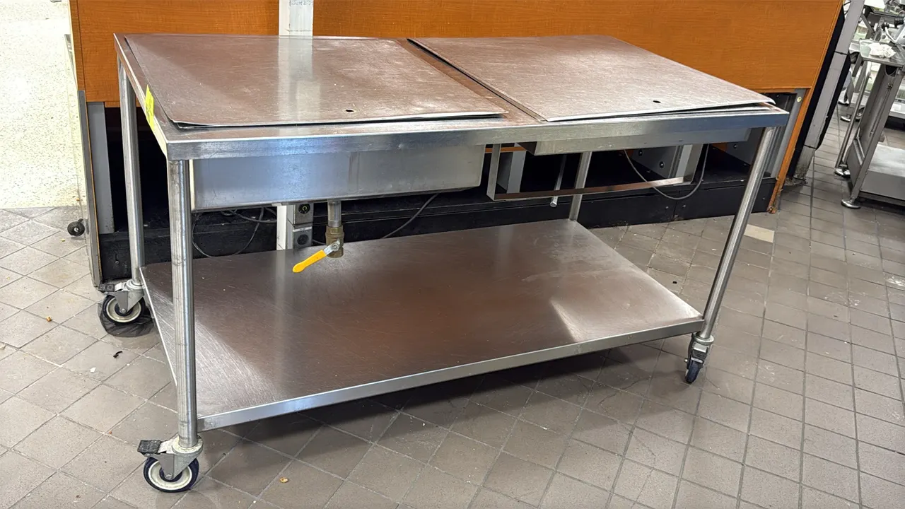 Stainless steel portable glazing and icing table. Features left rectangular glazing well with bottom drain and shut-off ball valve, right 4-hole conta