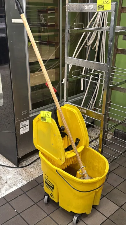 Rubbermaid WaveBrake mop bucket with wringer. Features yellow plastic construction and bail carry handle. Mounted on swivel casters. Includes mop with