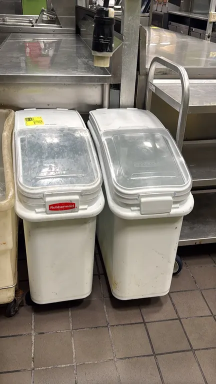 Rubbermaid portable poly ingredient bins. Features white polyethylene construction with clear flip-up access lids and front handles. Mounted on caster