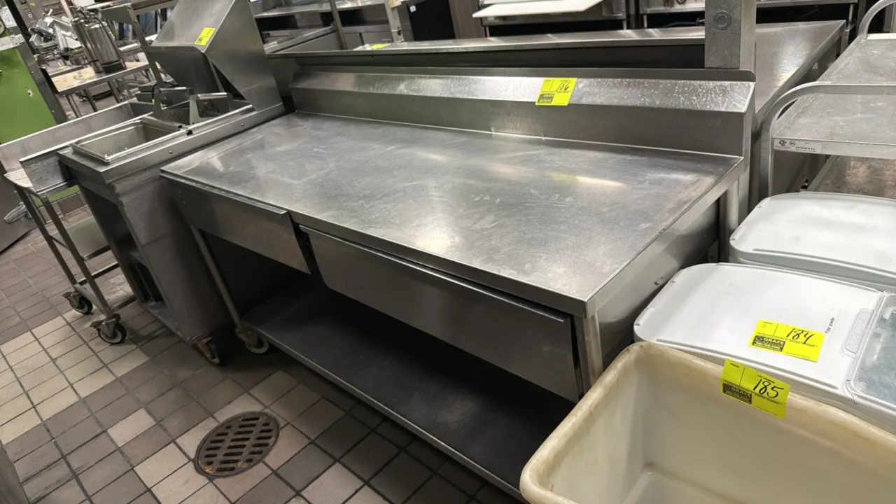 Stainless steel work table. Features a backsplash, (2) drawers, and an undershelf. Measures 72" x 24". Mounted on casters.