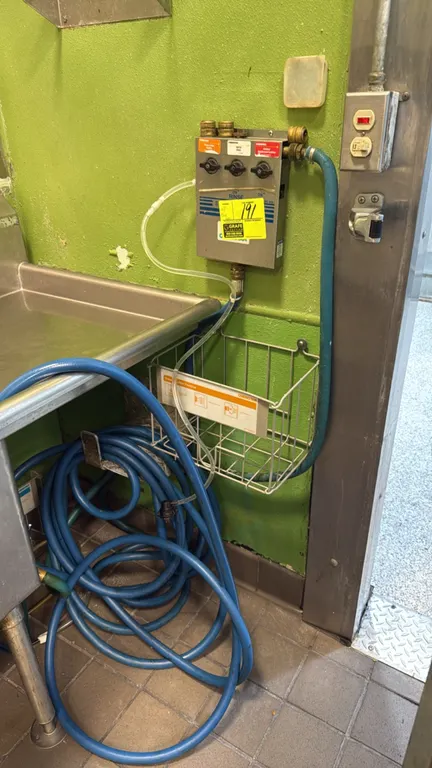 Chemstar chemical dispensing station. Features stainless steel housing with 3-product selector valves, intake tubing, wire chemical jug basket, and bl