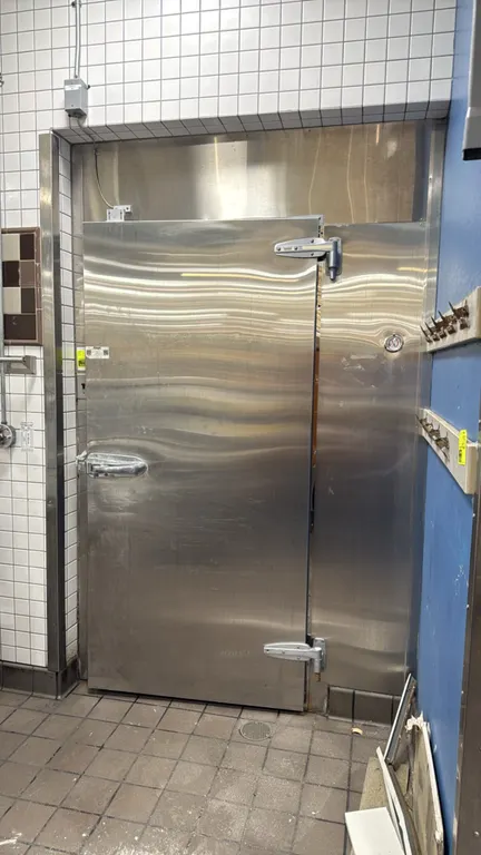 Kysor walk-in cooler. Features insulated foam panels, hinged access door with latch and exterior thermometer, interior ceiling lighting, and a Bohn 2-